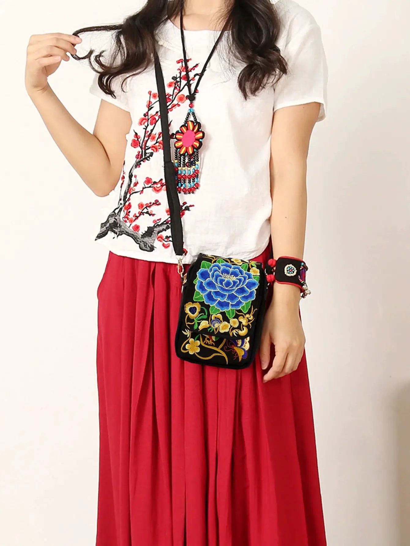 Small black canvas crossbody phone bag by Simples Market with colorful floral embroidery