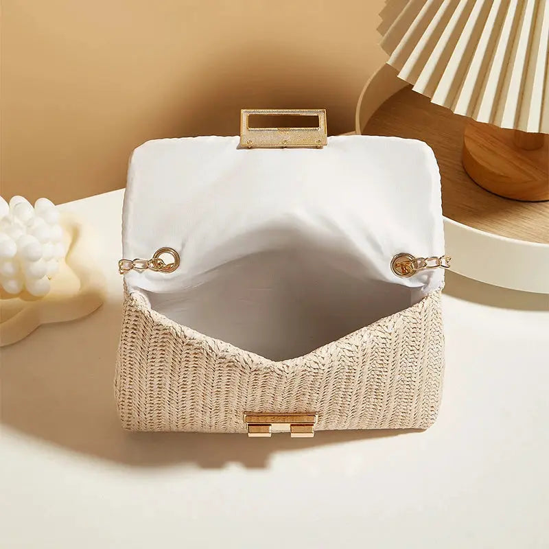 Crossbody bag for women with beige woven straw body, white fabric flap, and gold-tone chain strap.
