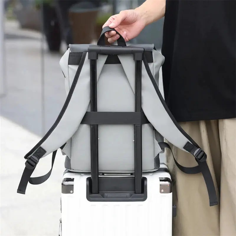 Backpack by Simples Market, grey waterproof with black straps, shown on luggage