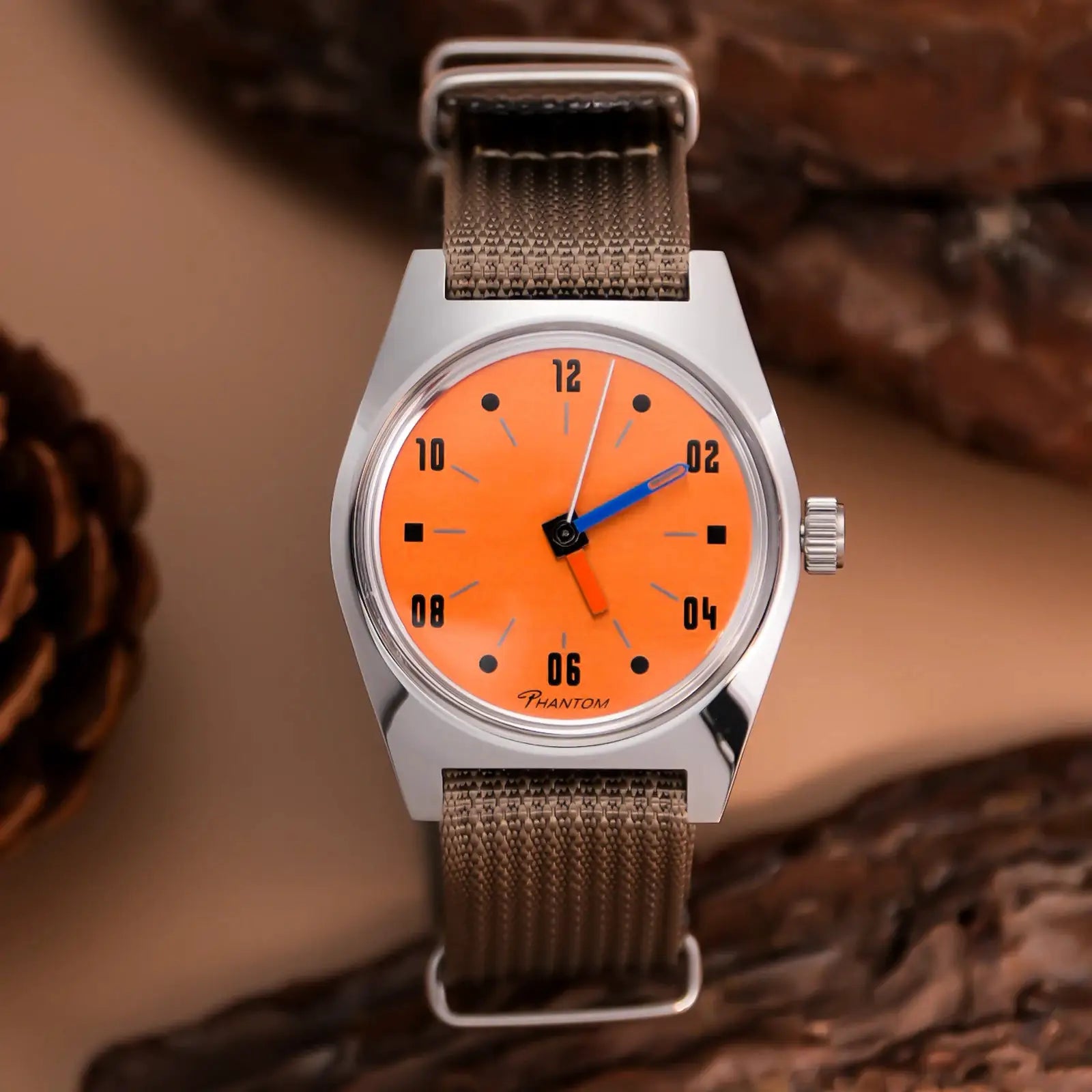 Men's 36mm hand-wind mechanical watch with orange dial and brown mesh strap.