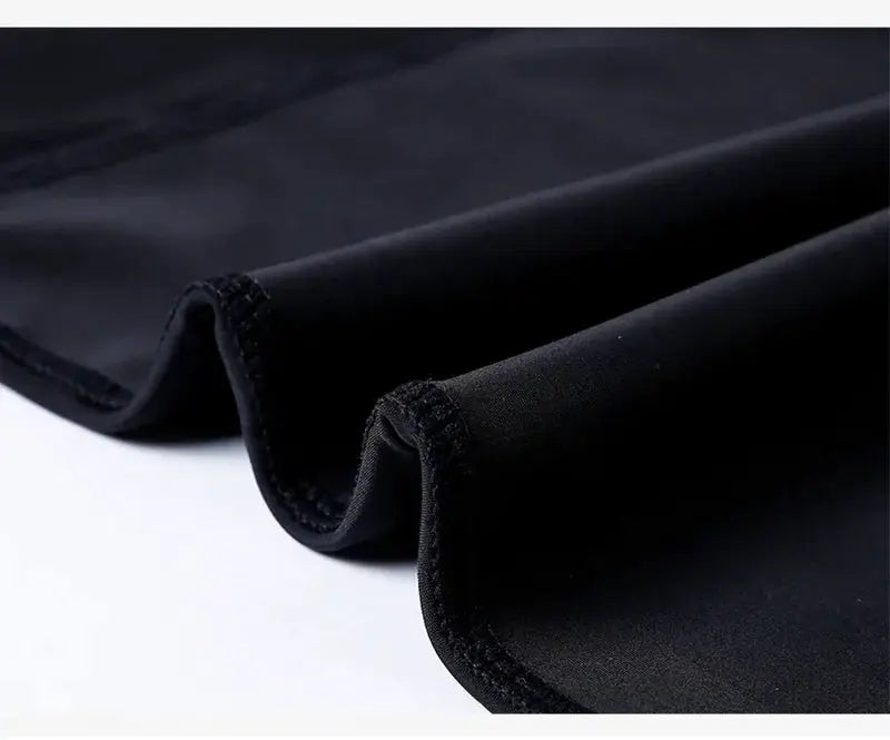 Men's gynecomastia shapewear vest in black fabric; short compression shirt material with curved hem edge