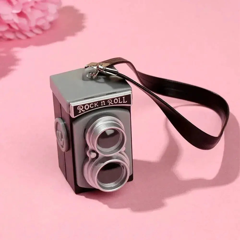 Dollhouse miniature SLR camera in gray/silver with black strap and Rock n Roll banner, 1/6–1/12 scale