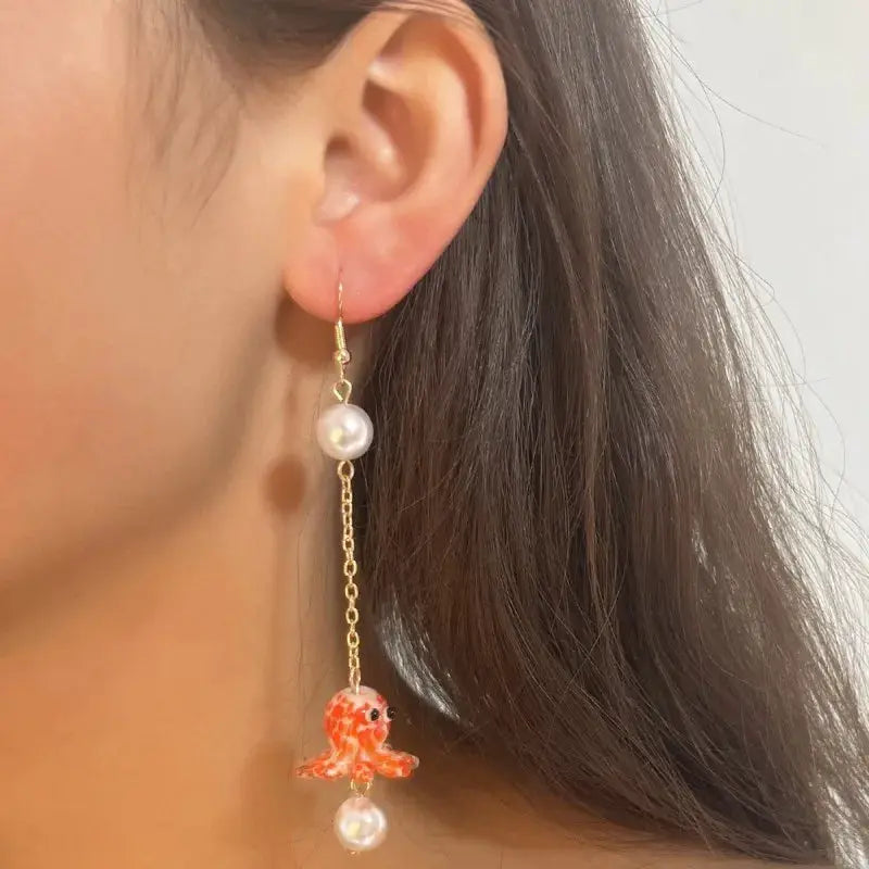 Cute octopus earrings with a long gold-tone chain, white pearls, and an orange glass octopus charm.