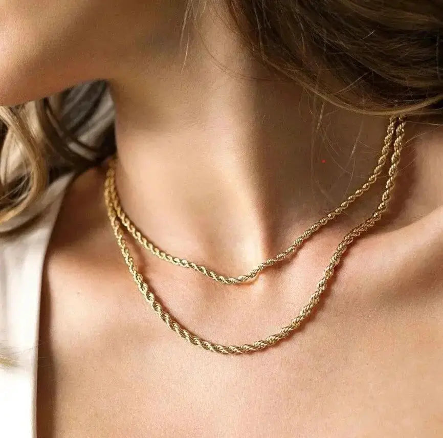 Two gold-tone rope chain necklaces, stainless steel, layered on a model's neck
