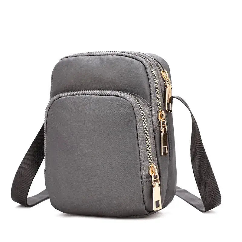 Crossbody bag by Simples Market, gray waterproof with front pocket and dual gold zippers