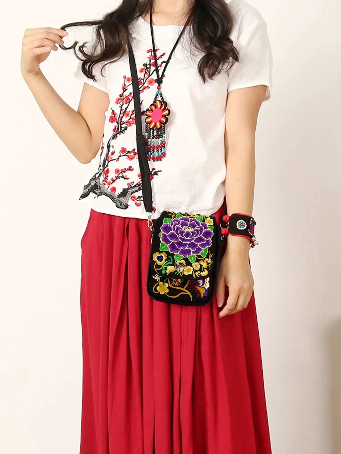Stylish women's embroidered crossbody phone bag with zipper; small black canvas purse with vibrant purple floral embroidery.