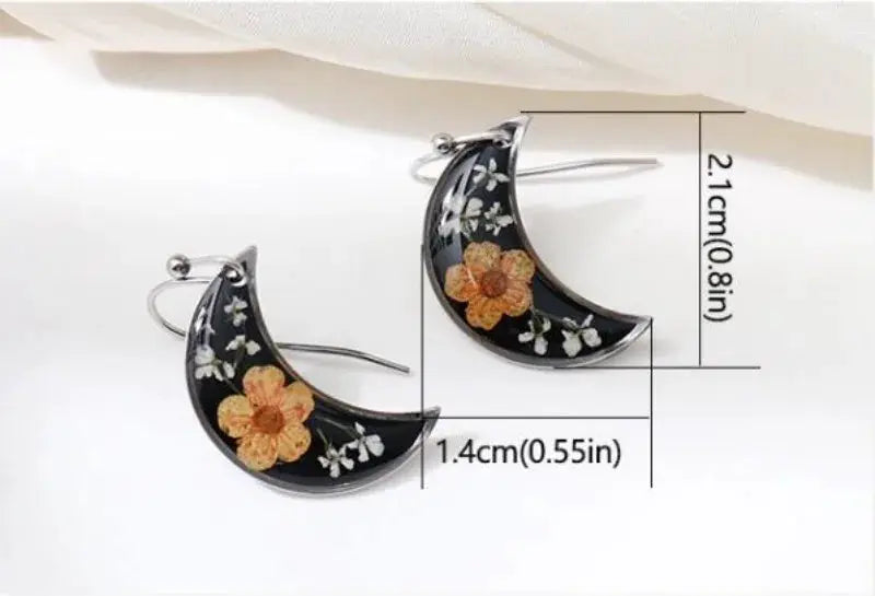 Crescent epoxy resin earrings with pressed orange flowers and white blossoms on black background; silver hooks.