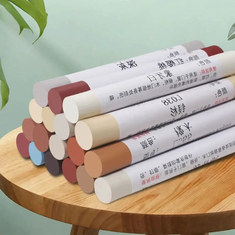 Simples Market waterproof wooden furniture repair pens in assorted cap colors, stacked on a wooden table.