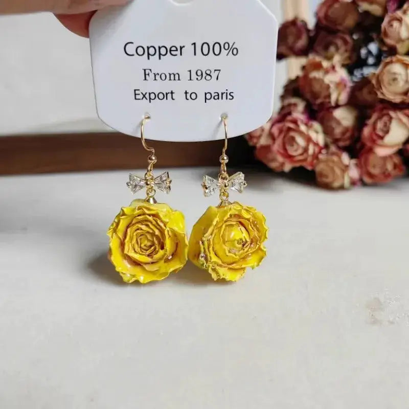 Yellow rose epoxy resin drop earrings with crystal bow accents and gold-tone hooks