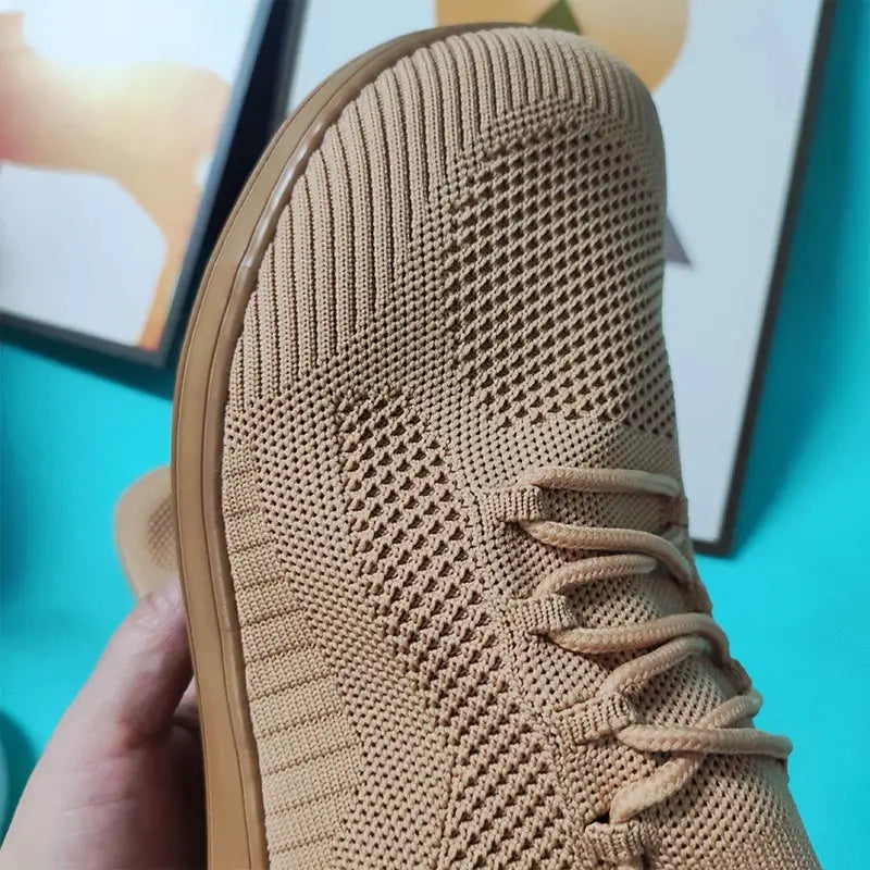 Breathable knit sneaker in beige with laces; minimalist hiking shoe with wide toe design.