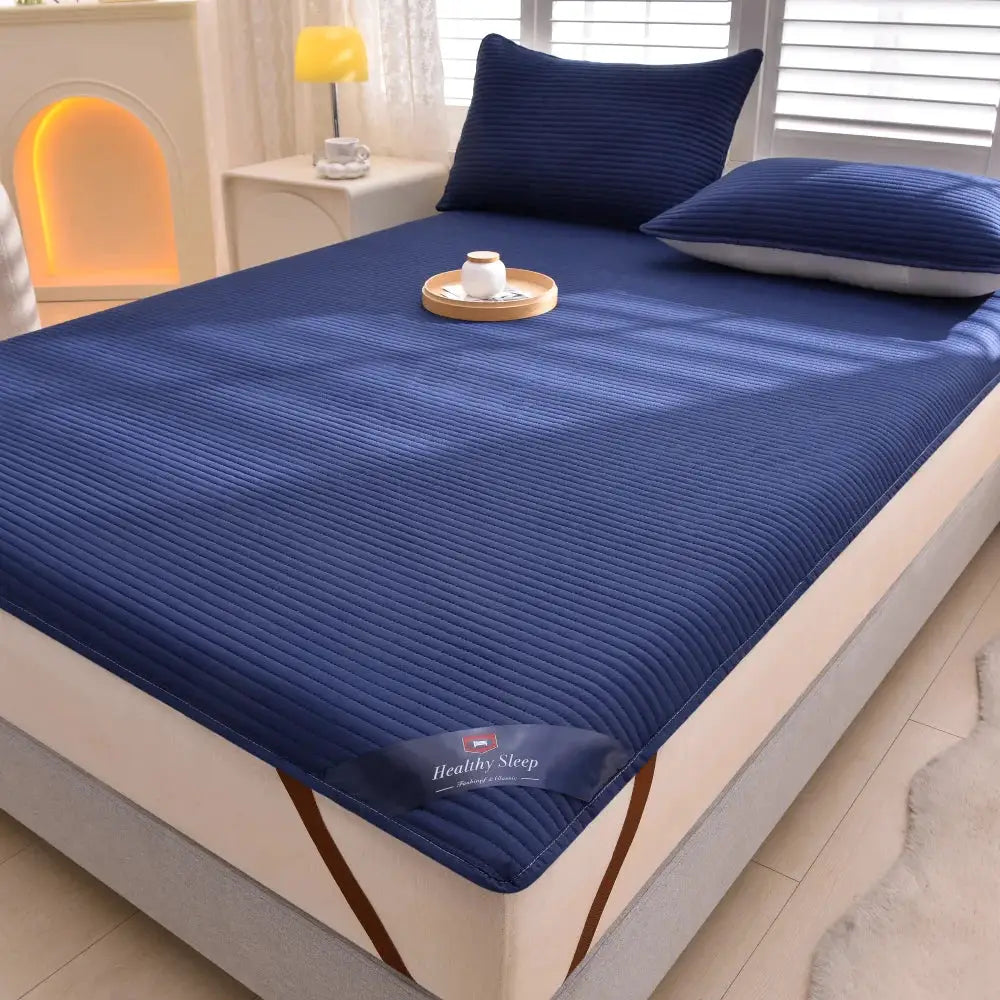 Striped navy blue waterproof mattress protector; soft, breathable, Healthy Sleep label on bed.