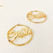 Pair of gold-tone stainless steel crown-name hoop earrings with scripted name by Simples Market