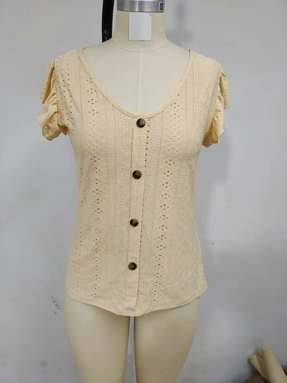Cream eyelet blouse with button-front closure and short puff sleeves on a mannequin.