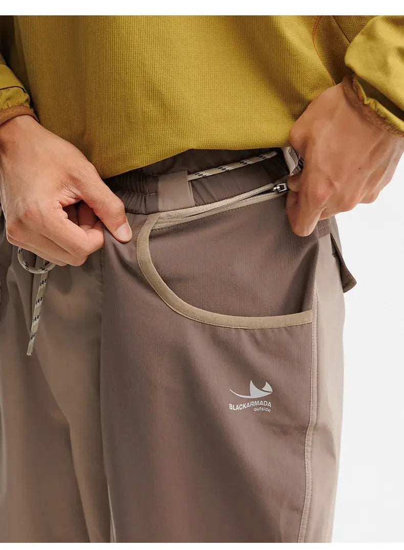 Men's outdoor cargo track pants in taupe with curved front pocket and Blackarmada outside logo