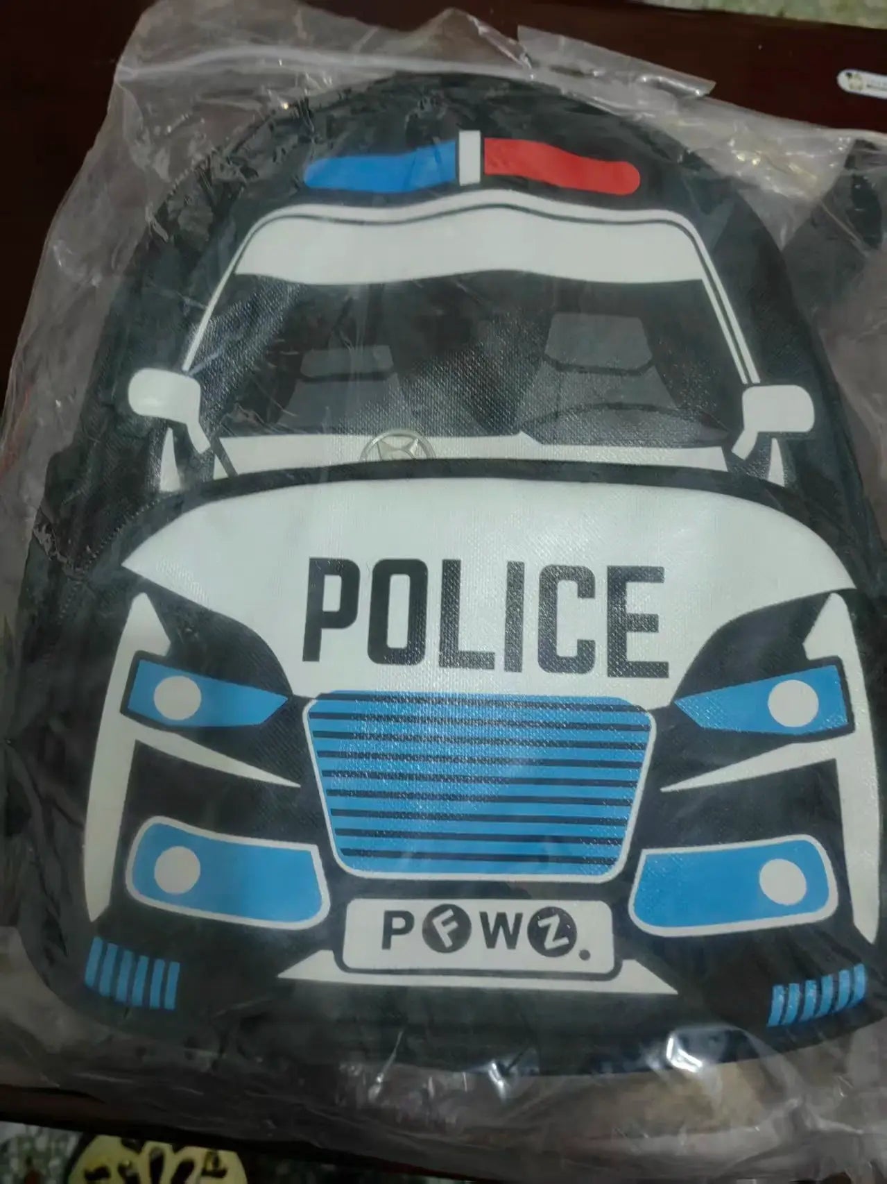 Police car schoolbag for kids by Simples Market, black with white police car graphic and blue accents.