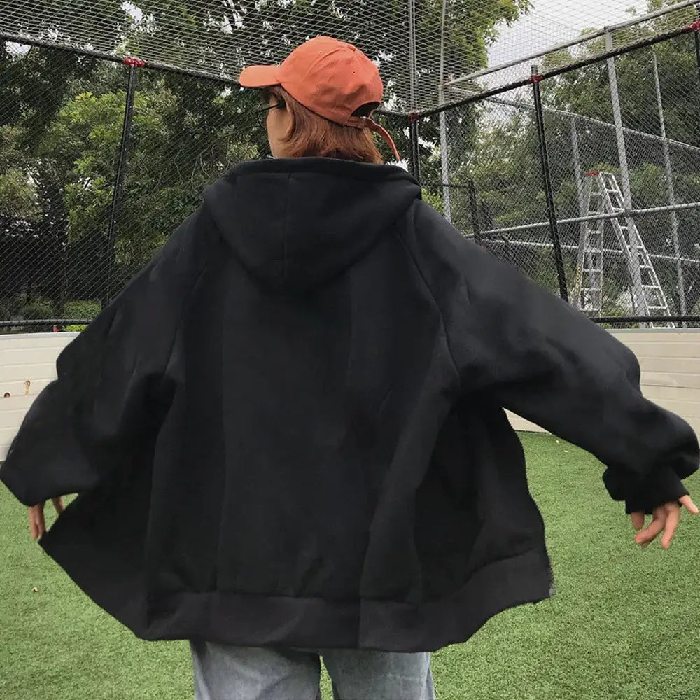 Hooded sweatshirt, black oversized fit, worn by a person outdoors; casual sportwear.