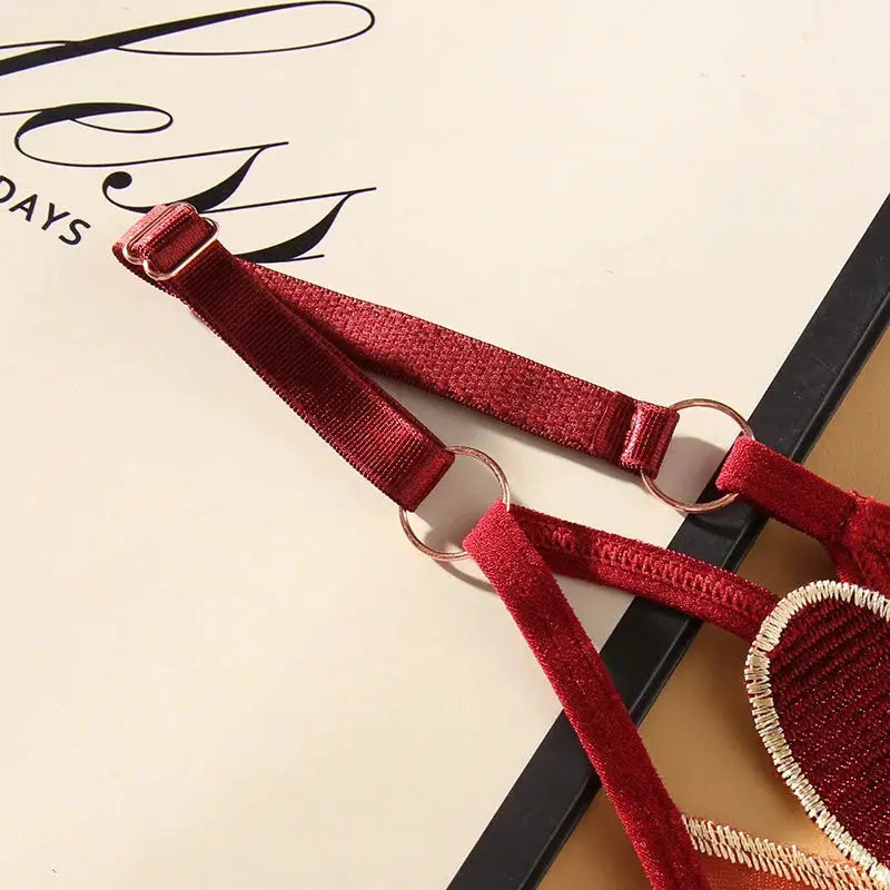 Red adjustable lingerie strap set with two velvet straps, metal rings, and a beaded circular patch