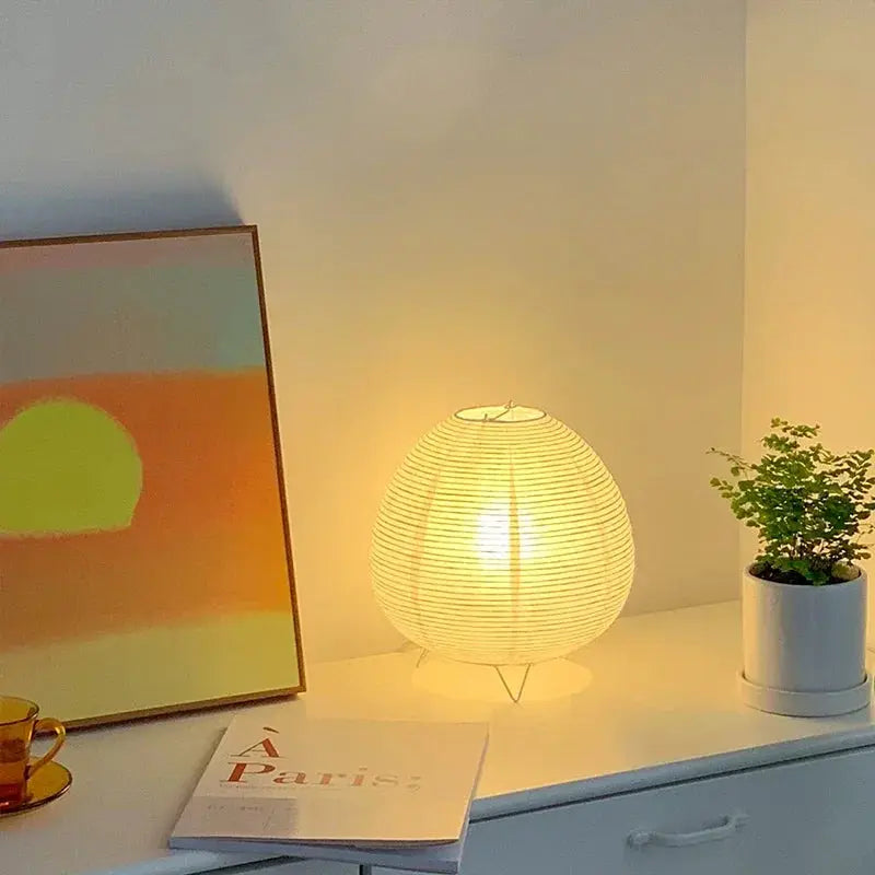 Japanese lantern LED table lamp with rice paper shade, warm glow on a white desk beside art and a plant