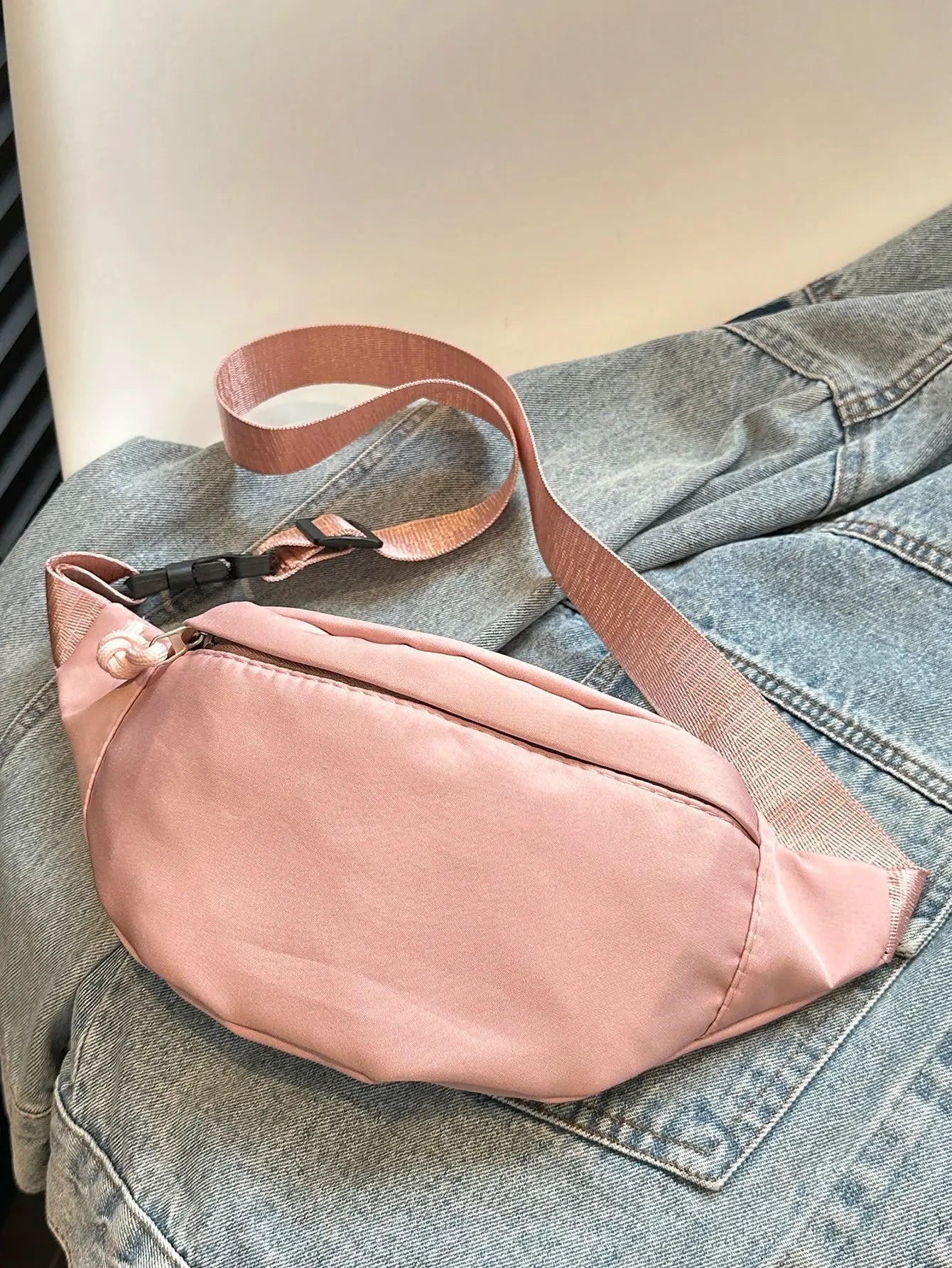 Fanny pack pink waist bag with adjustable strap on blue denim jeans