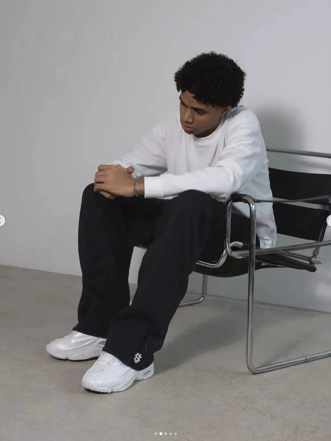 New Y2K pants by Simples Market; black straight-leg hip-hop joggers, worn by model seated in a studio.