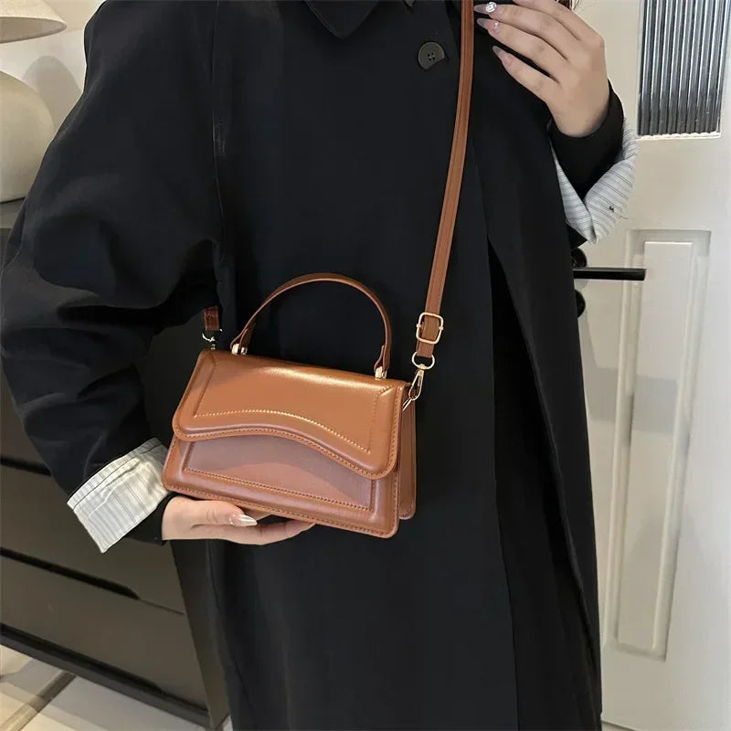 Crossbody handbag in tan brown PU leather with curved flap and top handle