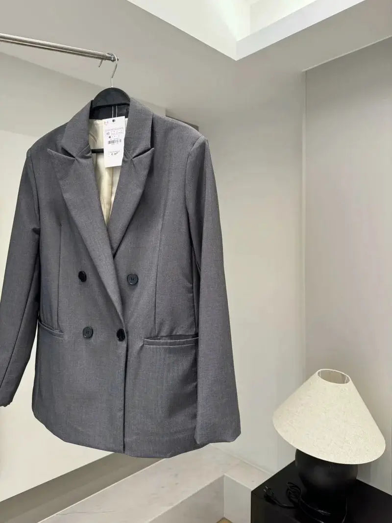 Blazer in gray, double-breasted with padded shoulders on a hanger.