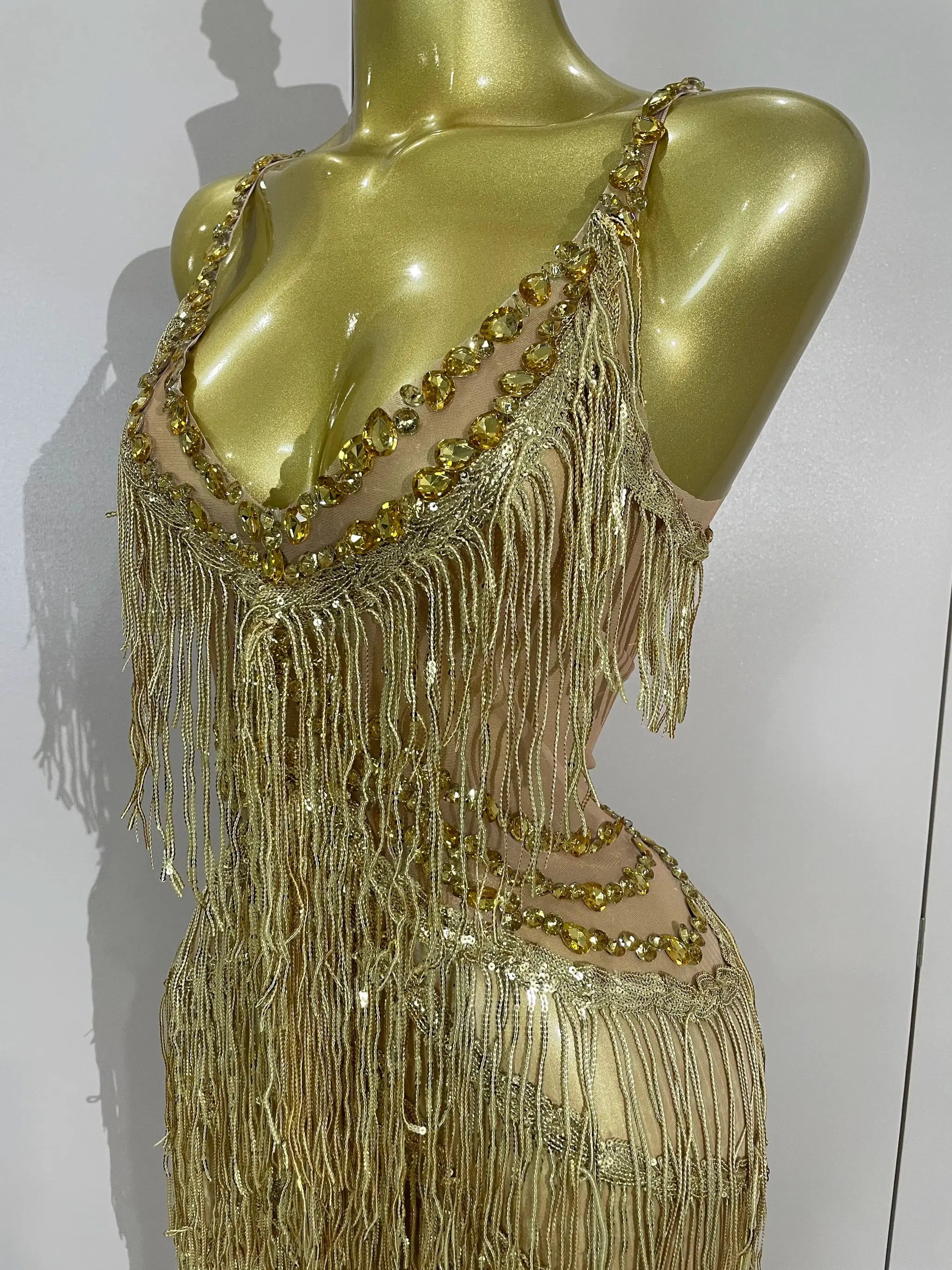 Gold-tone rhinestone fringe jumpsuit on a mannequin with long beaded fringe detailing.