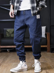Plus-size men's denim jogger jeans with elastic cuffs, dark blue, front patch label