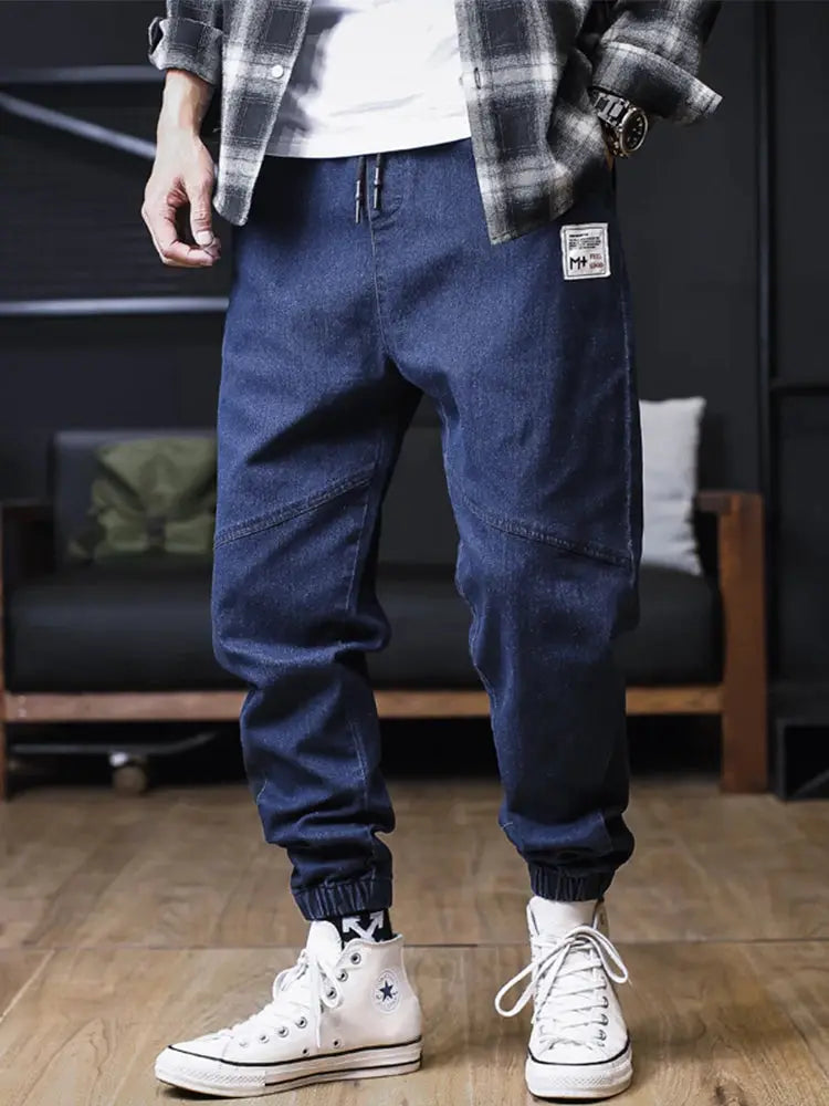 Plus-size men's denim jogger jeans with elastic cuffs, dark blue, front patch label