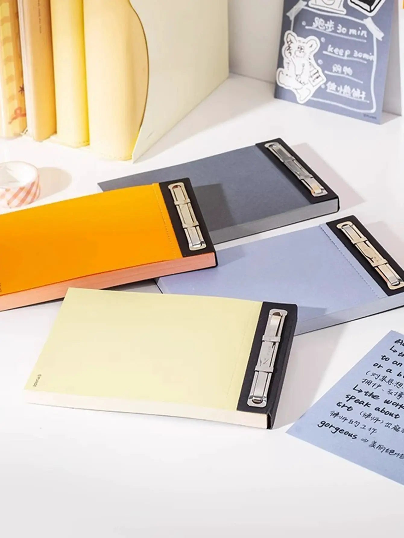 Notebooks set of four by Simples Market; tear-out pages, orange gray blue and yellow with metal binder clips.