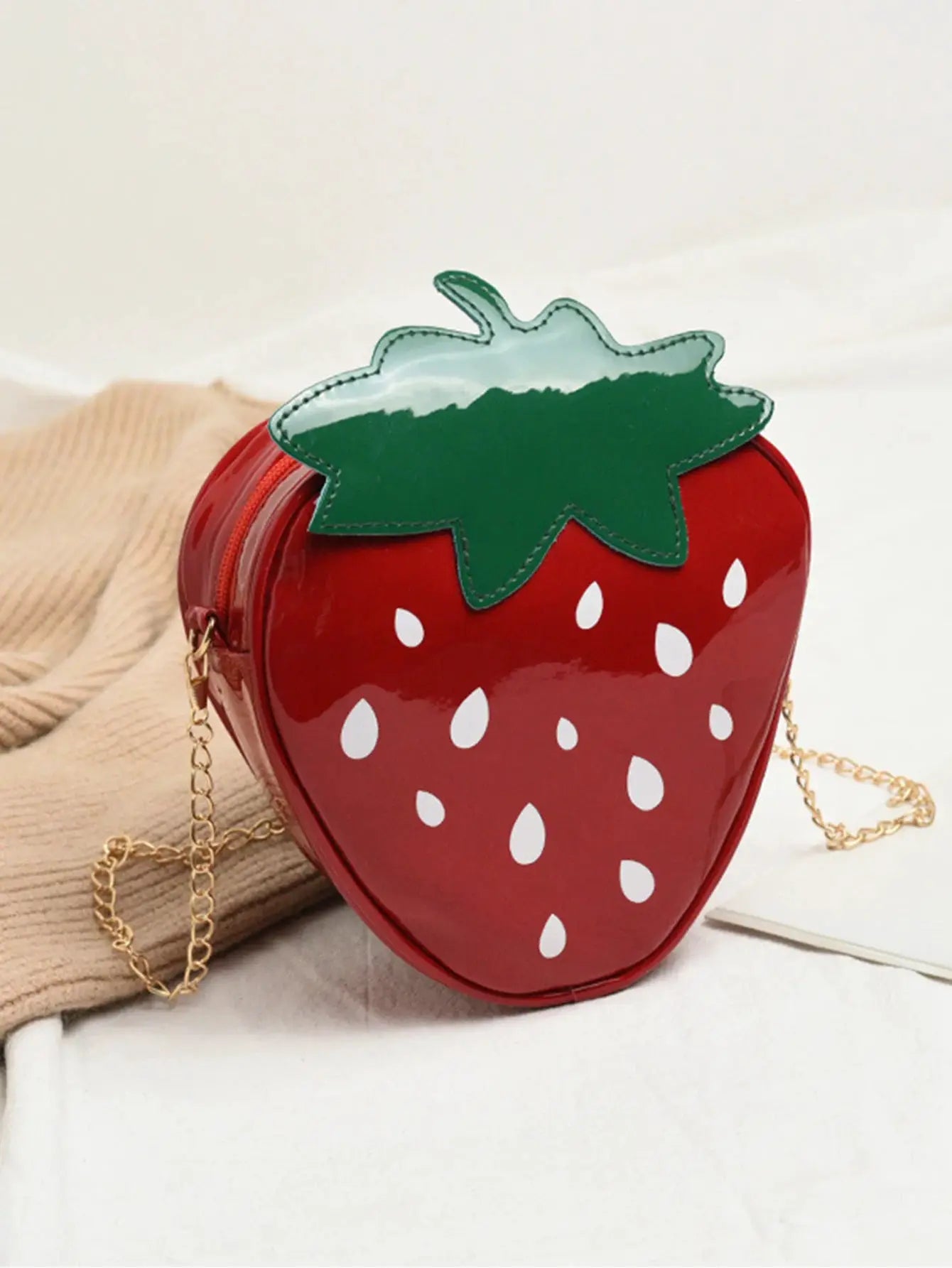 Strawberry-shaped crossbody bag in red with green leaf and gold chain strap