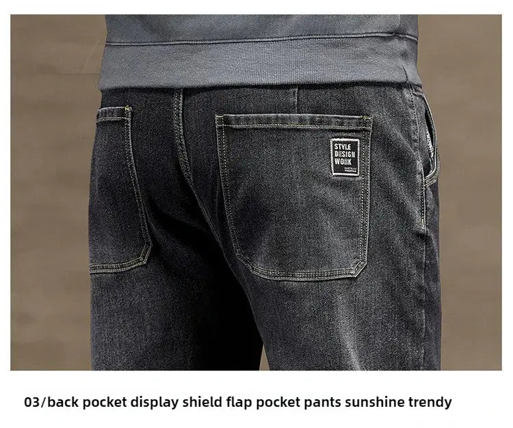 Men's dark denim jeans back view with two rear pockets and a small logo patch on the right pocket.