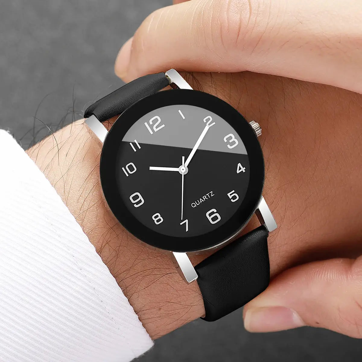 Wristwatch with black leather strap, silver case, and two-tone gray/black dial with quartz movement