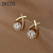 SKEDS gold-tone cross-stud earrings for women; pair with large central clear crystal and crystal-embellished curved bar.