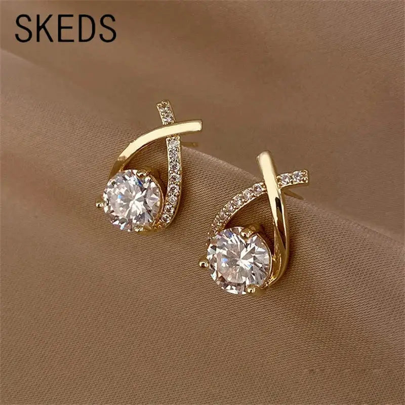 SKEDS gold-tone cross-stud earrings for women; pair with large central clear crystal and crystal-embellished curved bar.