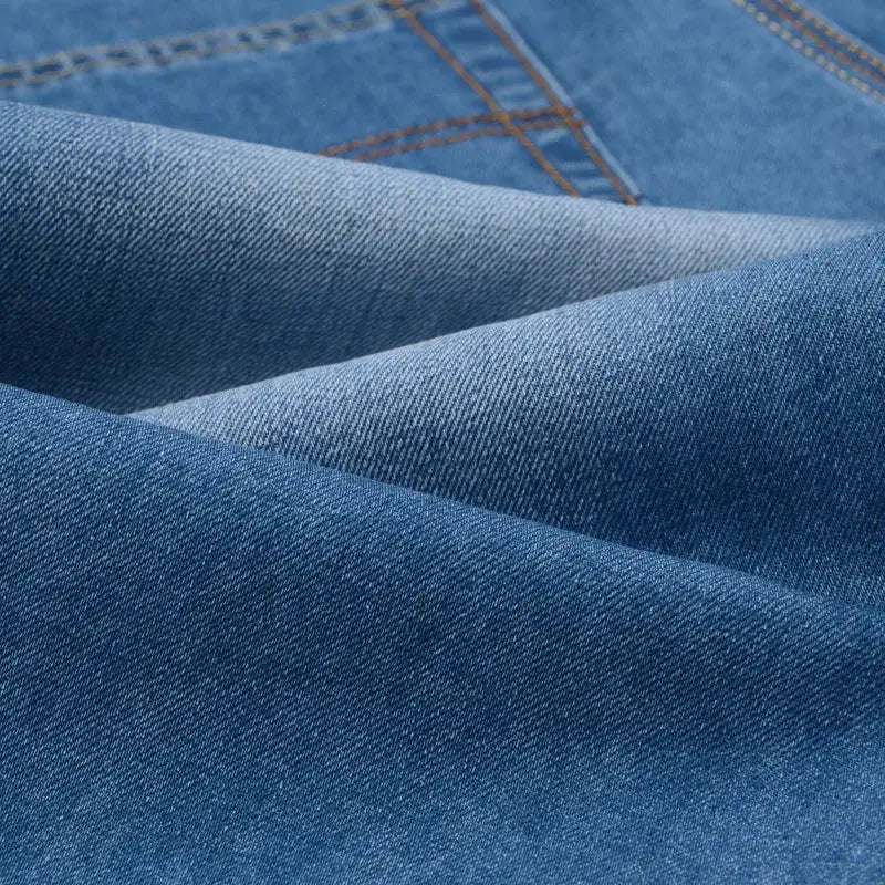 Men's denim shorts fabric close-up in light blue with orange stitching