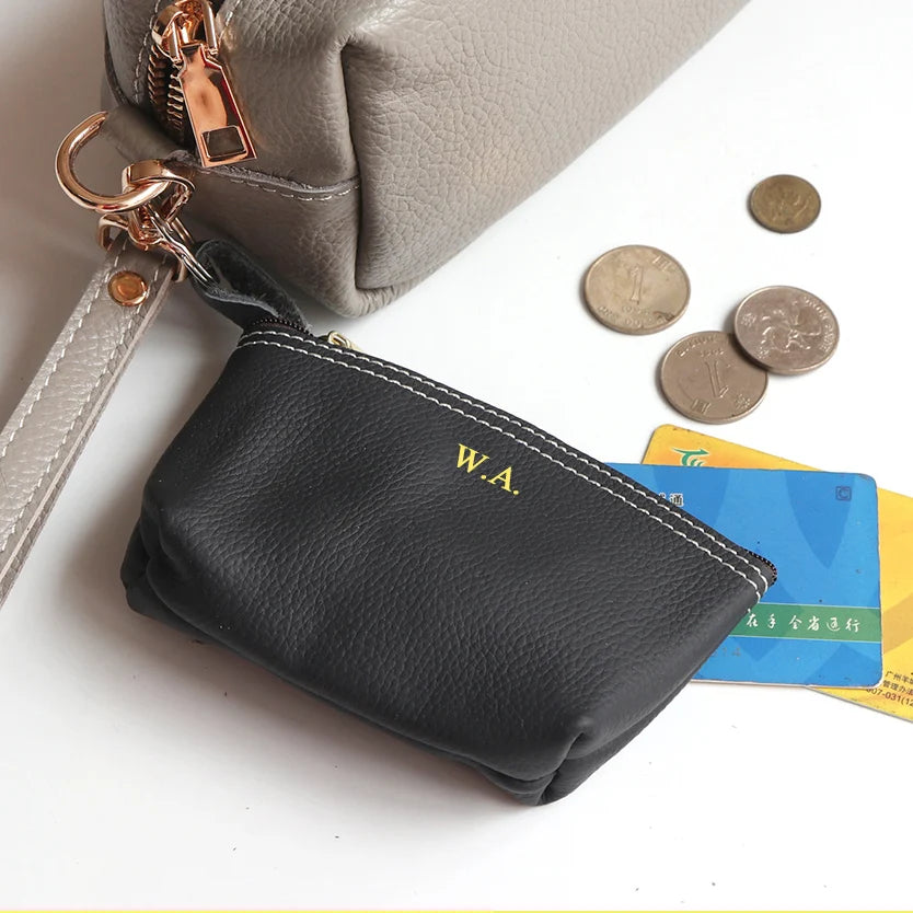 Genuine leather black card holder with white stitching and gold W.A. initials; two items shown, a beige bag in the background.