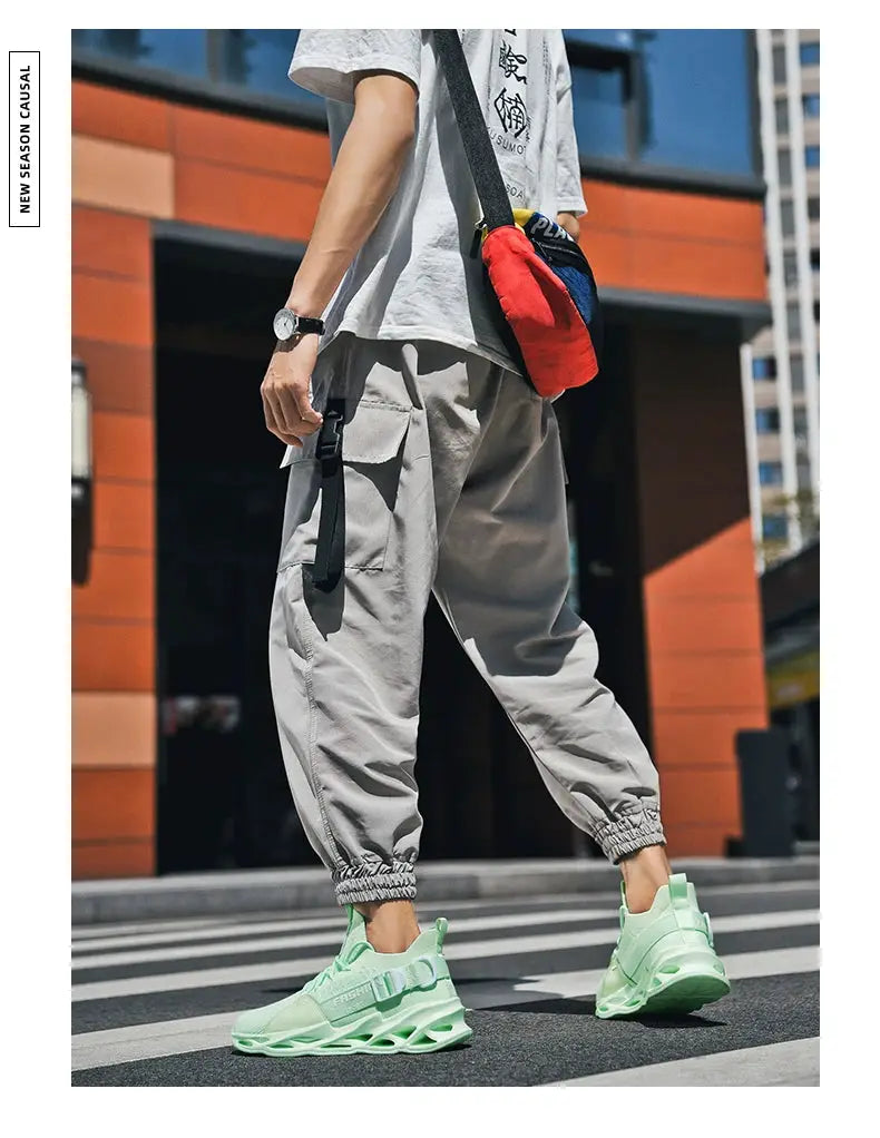 Sneakers mint green mesh athletic shoes with a chunky thick sole, worn by a person in gray cargo pants.