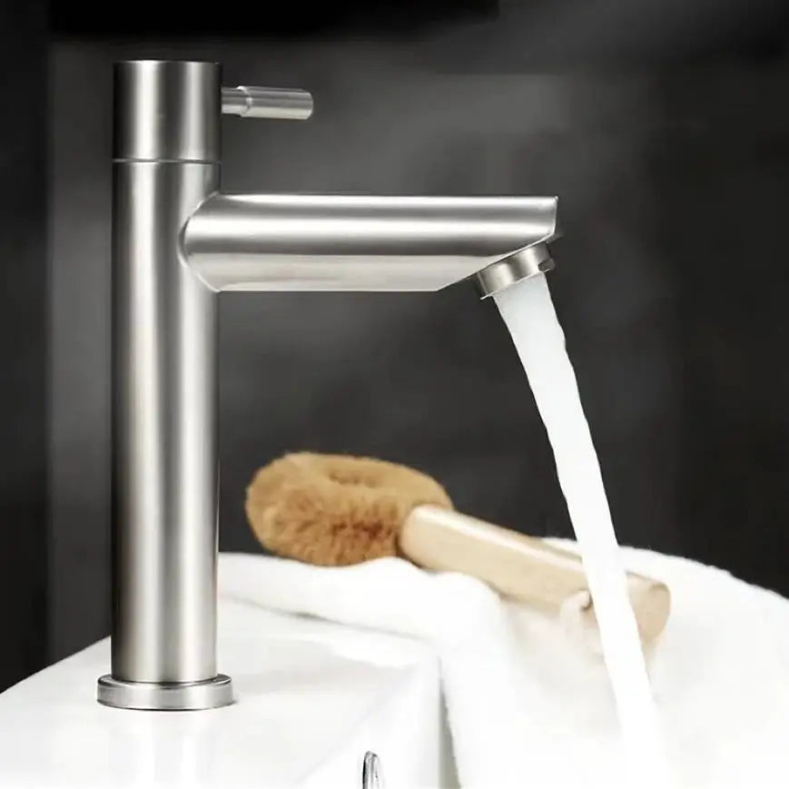 Stainless steel deck-mounted single cold basin tap with cylindrical body and flowing water.