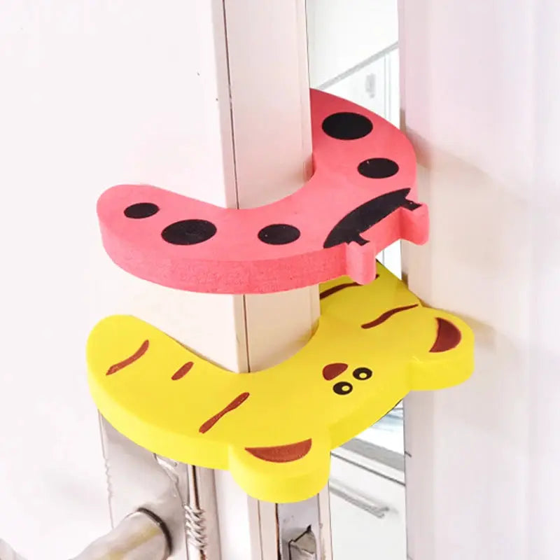 Baby safety door stoppers, 2-piece cartoon animal set by Simples Market in pink and yellow.