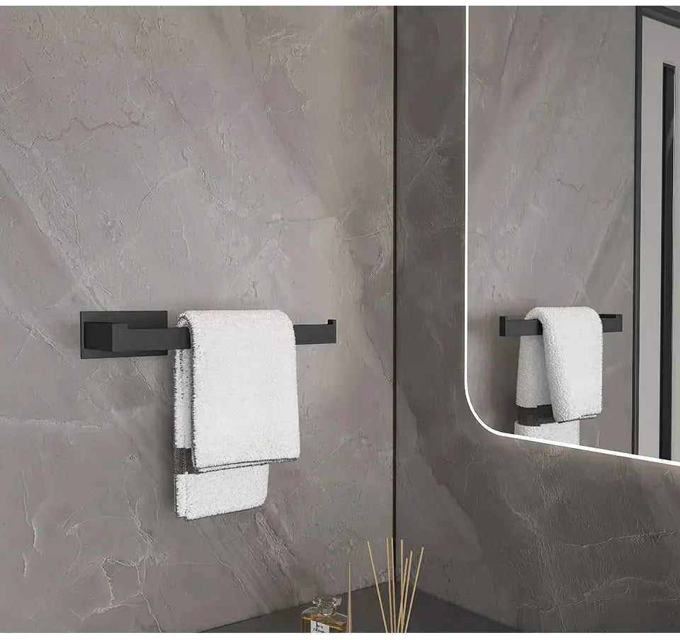 Black self-adhesive bathroom hardware set with towel bar mounted on gray tiled wall