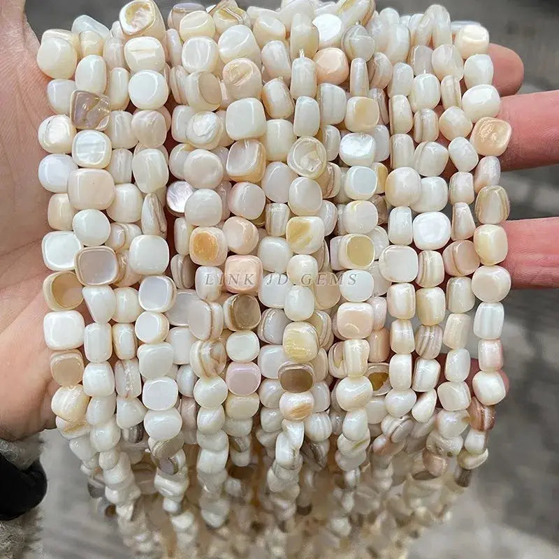 Natural shell beads, irregular smooth shapes, loose spacer beads for jewelry making in off-white to beige tones.