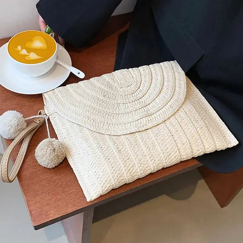 Handmade beige straw crossbody bag with envelope flap and pom-pom tassels