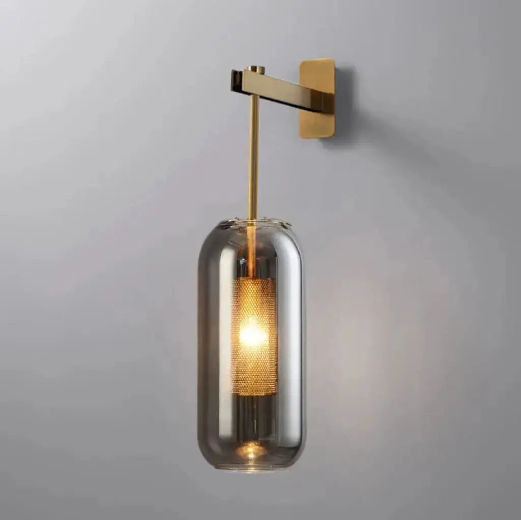 Modern glass wall light sconce, brass finish with clear cylindrical shade and LED bulb