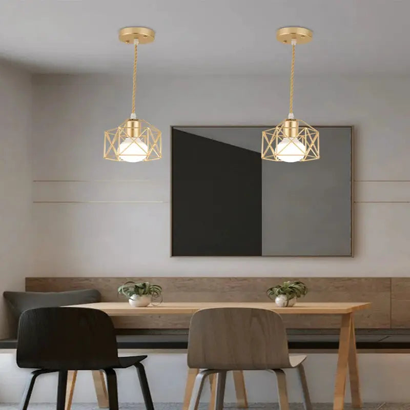 Modern LED pendant light in iron-gold minimalist metal cage, twin fixtures over a dining table.