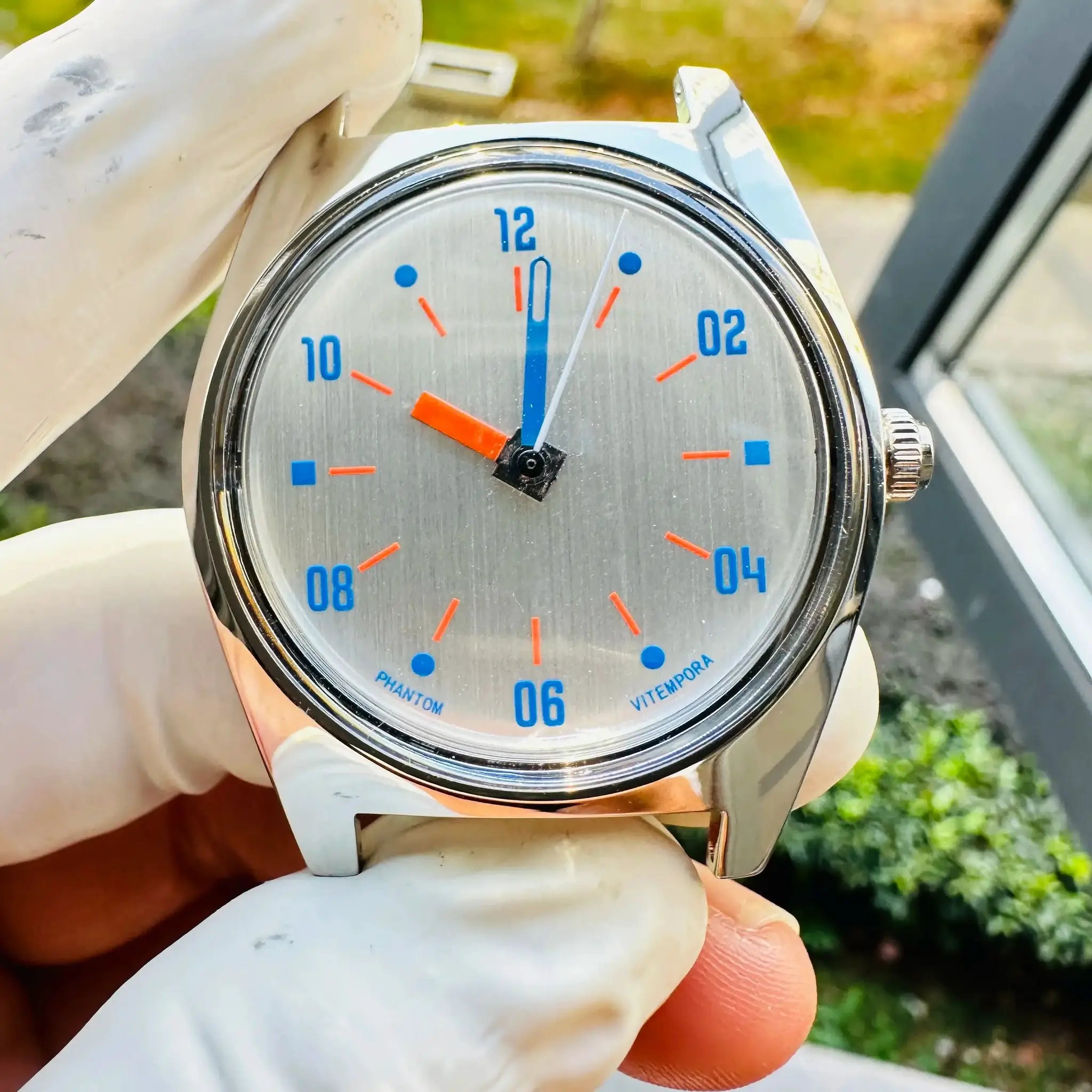 Simples Market 7120 hand-wind mechanical watch, 36mm, silver case with blue numerals and orange hands, white strap.