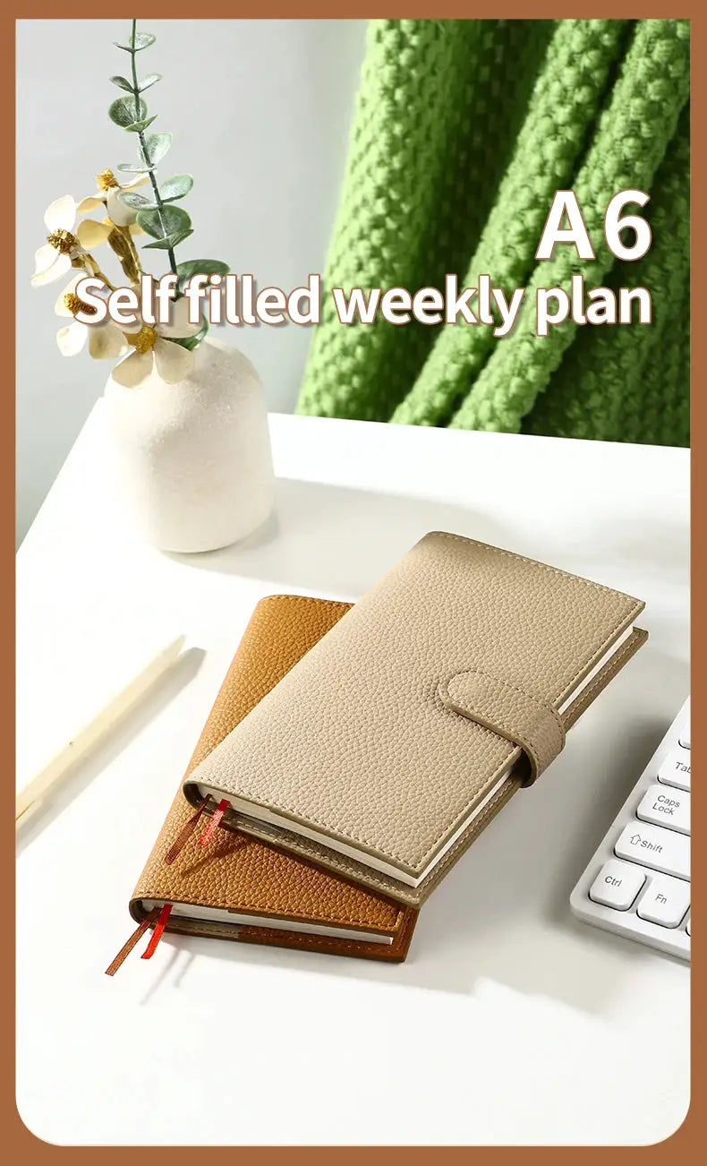 A6 weekly planner notebooks, two shown, pebble leather covers in beige and tan with red and orange bookmarks.