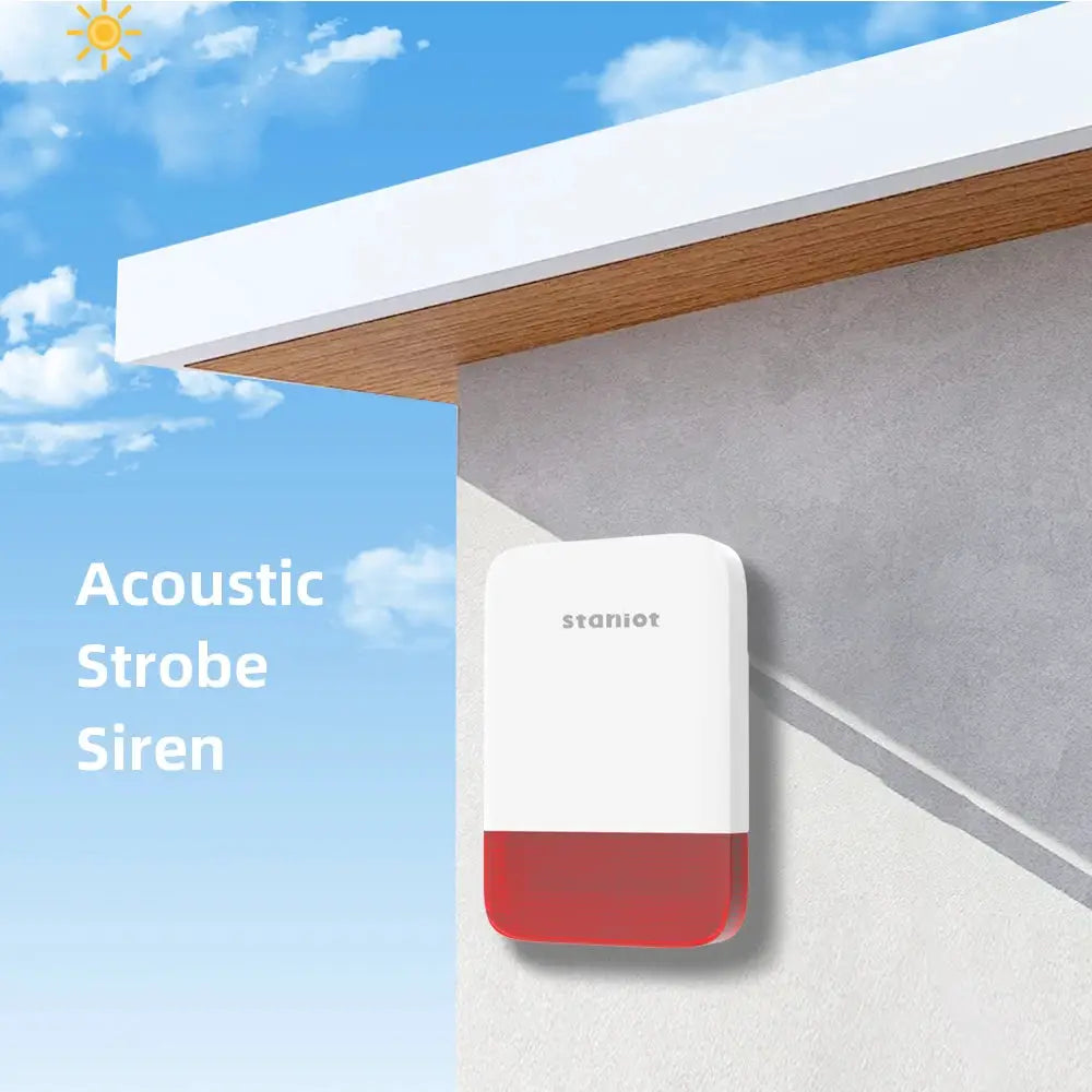 Staniot wireless strobe siren mounted on an outdoor wall; white housing with red base.