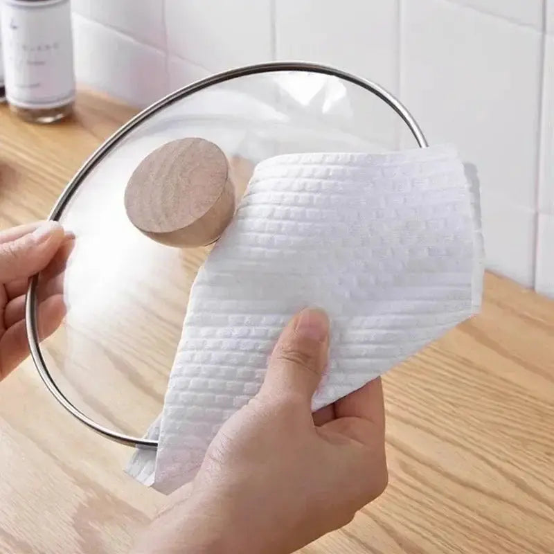 White non-woven kitchen cleaning cloth used to wipe a pot lid