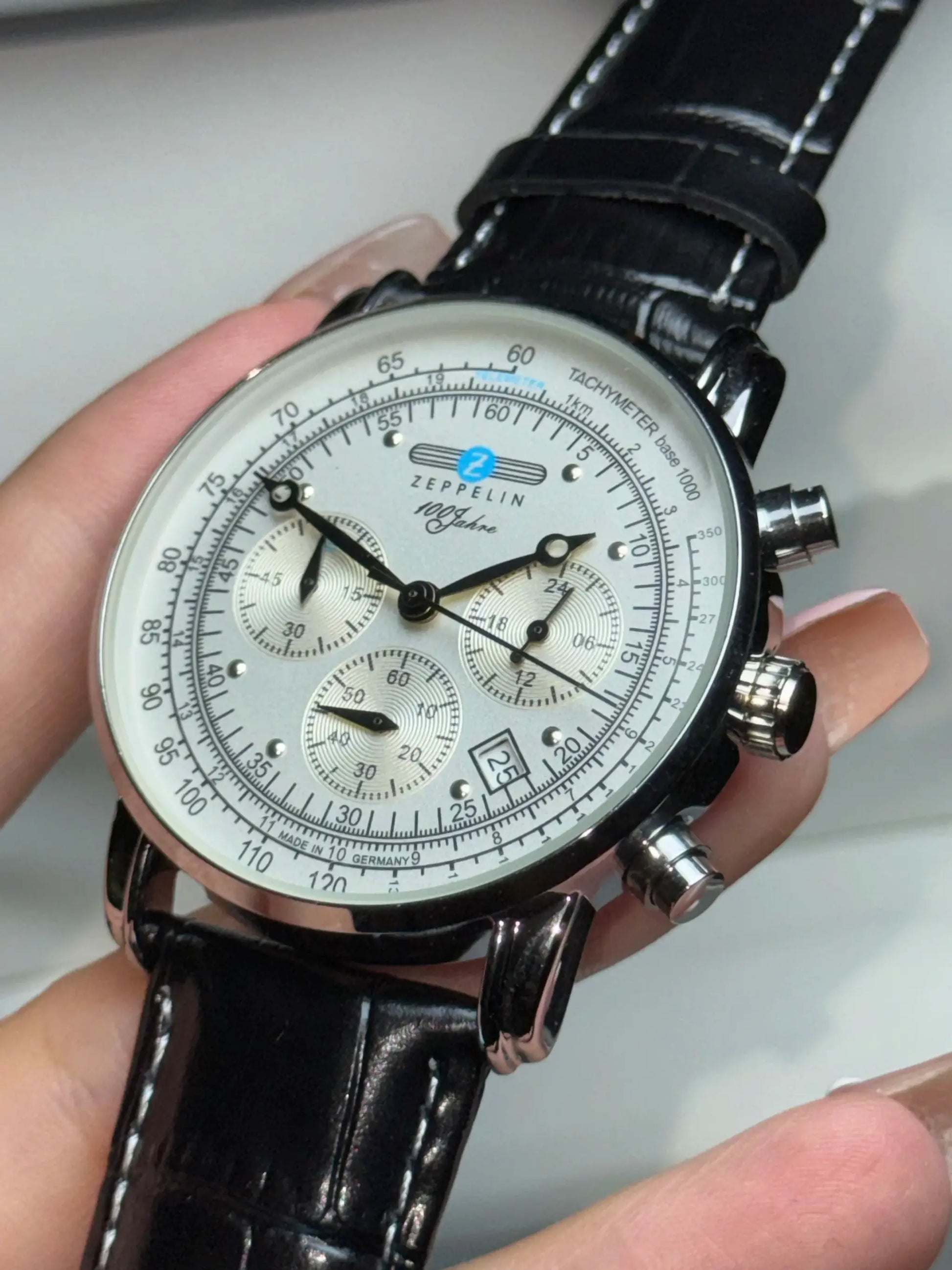 Zeppelin automatic men's chronograph watch with white dial, tachymeter, and black leather strap.
